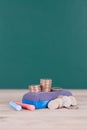 A blackboard eraser, a pile of dollar coins and two pieces of chalk in front of the blackboard background