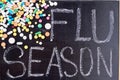 Blackboard with flu season words and pile of pills and tables.