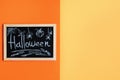 Blackboard with handwritten word `Halloween` and with funny chalk art on orange and yellow background Royalty Free Stock Photo
