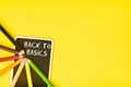 Blackboard and pencils with the text BACK TO BASICS on a yellow background, a business concept Royalty Free Stock Photo