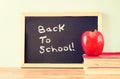 Blackboard with the phrase back to school, apple and stack of books. filtered image