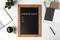 Blackboard with phrase GOALS 2023 and empty checklist on white wooden background, flat lay