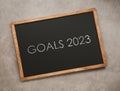 Blackboard with phrase GOALS 2023 on light grey stone background, top view