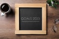 Blackboard with phrase GOALS 2023 on wooden background, flat lay