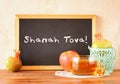 Blackboard with the phrase shana tova, apple, honey and pomegranate symbols of rosh hashanah holiday