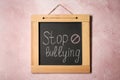 Blackboard with phrase Stop Bullying and prohibition sign on pink wall Royalty Free Stock Photo