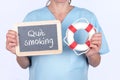 Blackboard with Quit smoking written on it and a lifebuoy in the hands of a doctor