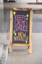 Blackboard sandwich board sign  on sidewalk outside clothing store in neon colors announcing new arrivals - Selective focus Royalty Free Stock Photo