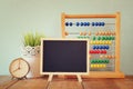 Blackboard, stack of colorful beaded abacus and clock. back to school concept Royalty Free Stock Photo