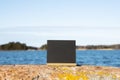 Blackboard standing on a rock. Blue sky with clouds and blue sea on background.