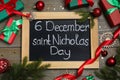 Blackboard with text 6 December Saint Nicholas Day, gift boxes and festive decor on wooden table, flat lay Royalty Free Stock Photo