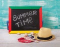 Blackboard with text it's summer time, accessories sunglasses, hat, towel on wooden deck Royalty Free Stock Photo