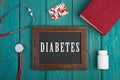 Blackboard with text & x22;Diabetes& x22;, stethoscope, pills and book on blue wooden background Royalty Free Stock Photo