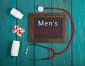 Blackboard with text & x22;Men& x27;s health& x22;, stethoscope, pills