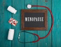 Blackboard with text & x22;Menopause& x22;, stethoscope, pills on blue wooden background Royalty Free Stock Photo