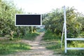 Blackboard with white frame hanging on tree branch in garden, copy space. Plate for text on rope. Blank black desk billboard. Natu Royalty Free Stock Photo