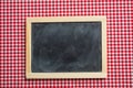 Blackboard with wooden frame on red checkered picnic tablecloth, copy space