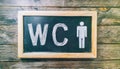 Blackboard with the word WC on a wooden background.