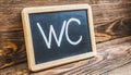 Blackboard with the word WC on a wooden background.