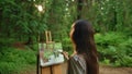 Blackhair woman paints a landscape oil painting in park