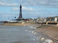 Scenic view of blackpool from the south with waves breaking on the steps, people on the promenade and the golden mile and tower in Royalty Free Stock Photo