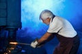 Blacksmith bending heated steel under press machine