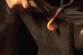 Close-up working powerful hands of male blacksmith forge an iron product in a blacksmith. Hammer, red hot metal and