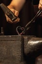 Close-up working powerful hands of male blacksmith forge an iron product in a blacksmith. Hammer, red hot metal and Royalty Free Stock Photo