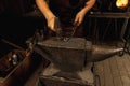 Close-up working powerful hands of male blacksmith forge an iron product in a blacksmith. Hammer, red hot metal and