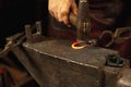 Close-up working powerful hands of male blacksmith forge an iron product in a blacksmith. Hammer, red hot metal and