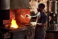 Blacksmith, fire and a black man melting metal in a workshop for manufacturing or industrial design. Factory, welding or