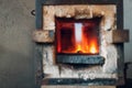 Blacksmith forge oven with hot flame. Smith heating iron piece of steel in fire of red-hot forge Royalty Free Stock Photo