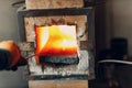 Blacksmith forge oven with hot flame. Smith heating iron piece of steel in fire of red-hot forge Royalty Free Stock Photo