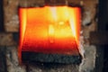 Blacksmith forge oven with hot flame. Smith heating iron piece of steel in fire of red-hot forge Royalty Free Stock Photo