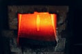 Blacksmith forge oven with hot flame. Smith heating iron piece of steel in fire of red-hot forge Royalty Free Stock Photo