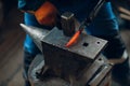 Blacksmith forges and makes metal detail with hammer and anvil at forge