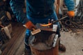 Blacksmith forges and makes metal detail with hammer and anvil at forge