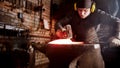 Blacksmith forging a knife blade in his workshop using a hammer