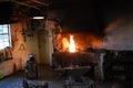 Blacksmith forging a nail in front of a blazing fire