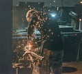 Blacksmith grinding a metal plate in smithy with spark fireworks. Royalty Free Stock Photo