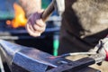 Blacksmith hammering iron rod on anvil in background fire Royalty Free Stock Photo