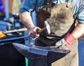 Blacksmith hammering iron rod on anvil in background fire Royalty Free Stock Photo