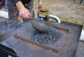 Blacksmith hand adding coal to a burning forge with a scoop. At the smithy workshop