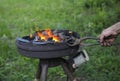 Blacksmith hand holding forceps with a metal billet in a burning forge