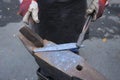 Blacksmith hands holding forceps and a hammer forging a metal billet, blade of a knife, on an anvil