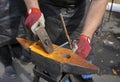 Blacksmith hands holding forceps and a hammer forging a metal billet nail on an anvil Royalty Free Stock Photo