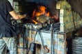 Blacksmith heats metal on fire in workshop. Working environment with tools in an old smithy
