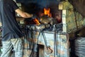 Blacksmith heats metal on fire in workshop. Working environment with tools in an old smithy