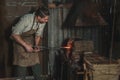 Blacksmith heats a metal part in a fire before forging it. Royalty Free Stock Photo