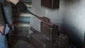 Blacksmith holding candent iron ingot and forging it using pneumatic hammer.